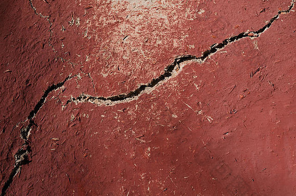 旧墙被涂成红色的粘土和稻草覆盖着。纹理、水平照片、壁纸