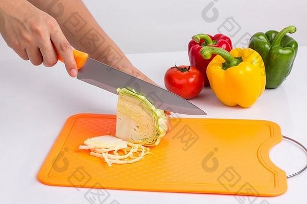 家庭主妇在白色背景的塑料切菜板上用刀切菜