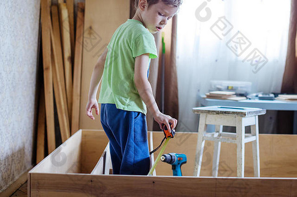 可爱的年轻的男孩卷测量木书柜架子上单位