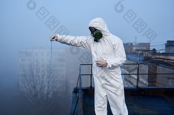 身穿防护服的科学家正在污染区高层建筑顶部的玻璃瓶中使用蓝色试剂进行研究