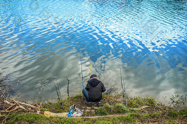 拿着鱼竿在湖里钓鱼的人