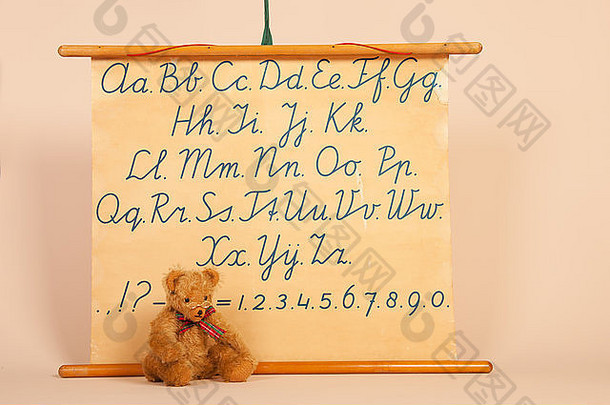 手工制作的熊坐在古董课前，上面有字母和数字