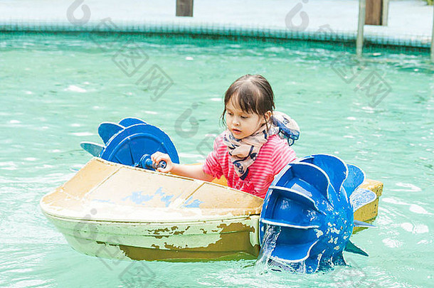 年轻的亚洲女孩在游泳池里蹬着船