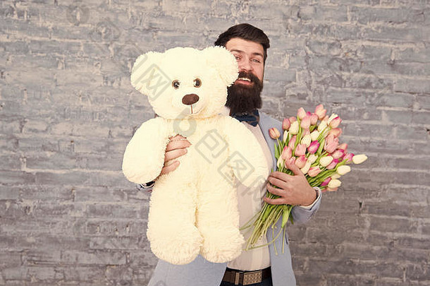 熊玩具。享受春假。留着胡子的男人，带着郁金香花束和熊。春天的礼物。留胡子的男人，带着花。<strong>可爱</strong>的熊。三月八号。爱情约会。<strong>国际</strong>假<strong>日</strong>。妇女节。大熊的礼物。