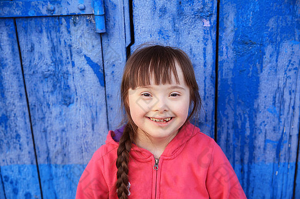在蓝色墙壁的背景上微笑的年轻女孩。