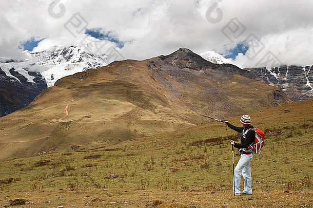 一名妇女在不丹徒步穿越山坡时，指着乔莫哈里山。