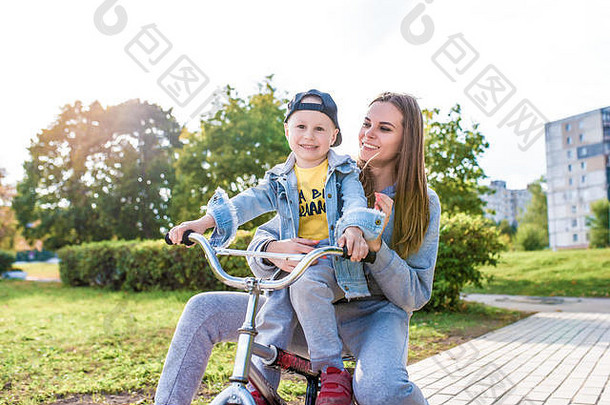 妈妈带着4-5岁的小男孩，学习骑自行车，欢笑，享受假期，在城市公园里度过<strong>夏秋</strong>
