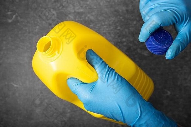 人类手保护手套持有黄色的漂白剂瓶消毒概念