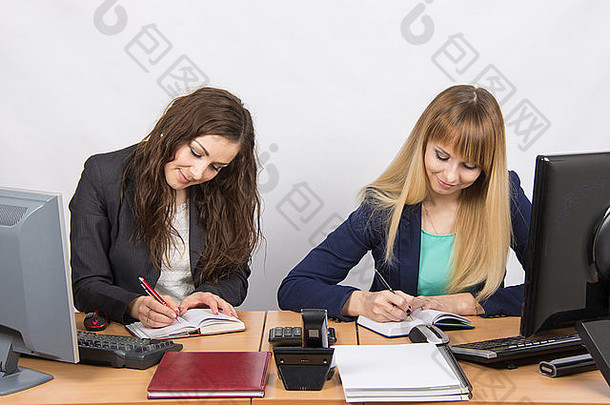 坐在办公桌旁的两位年轻漂亮的女商人被分成了两份工作