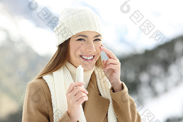 一个快乐的女人在脸上涂保湿霜的肖像，背景是雪山