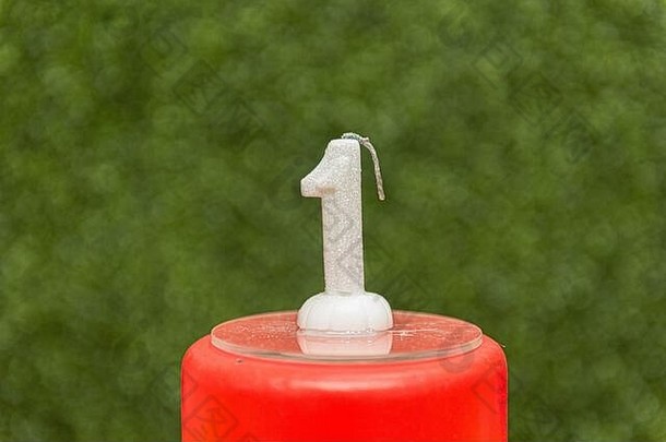 红色假蛋糕的顶部有<strong>一</strong>个形状模糊的绿色背景蜡烛。白色的<strong>一</strong>周年庆祝活动。儿童生日晚会