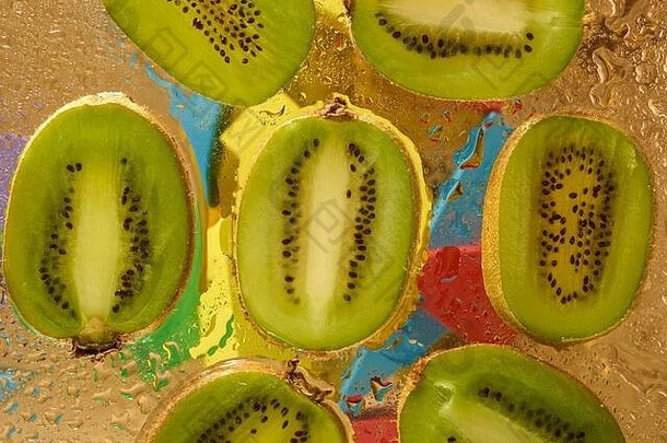 成熟多汁猕猴桃片，背景颜色鲜艳，由水滴构成