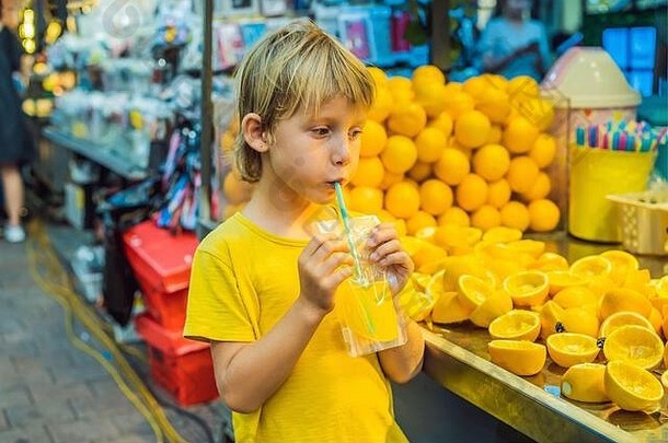 这个小男孩在首尔的一条步行街上喝着<strong>鲜榨</strong>橙汁。新鲜<strong>果汁</strong>在韩国是一个很受欢迎的旅游景点。前往