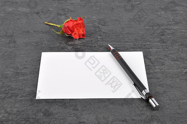 备忘录、钢笔和石板上的红玫瑰