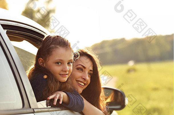 快乐旅行微笑的母亲和小女孩在美丽的自然背景下看着车窗