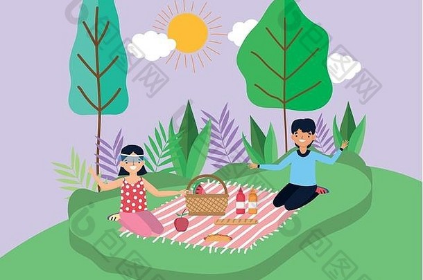 这对年轻夫妇坐在公园里的毯子上野餐
