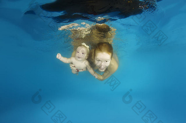 妈妈和小女孩在游泳池里的水下游泳课上学习水下游泳