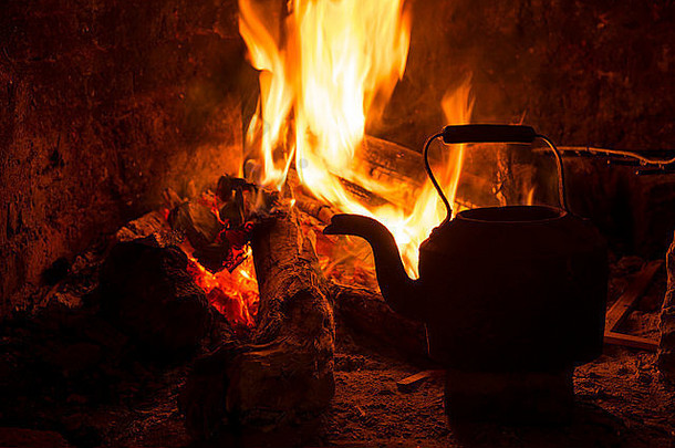 水壶在壁炉里，火和木头燃烧。舒适的寒假小屋场景。