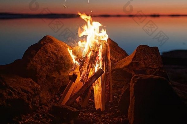 夜间海滩上的篝火和大气中的火焰。湖底的静水，太阳的暖色