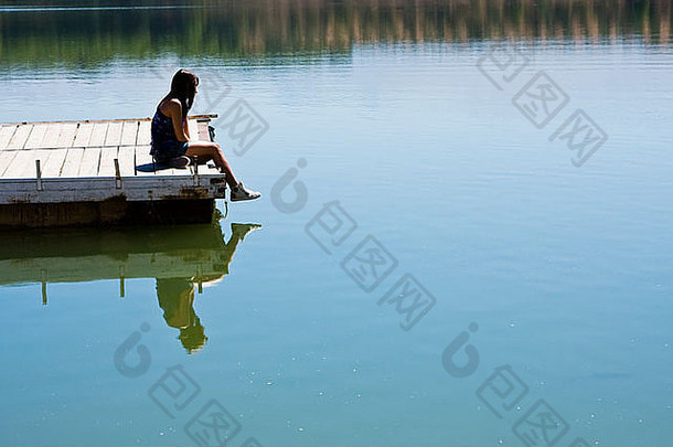 年轻的女孩坐着码头湖