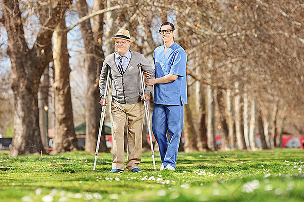 阳光明媚的日子里，一位老人和一位男护士在公园里散步