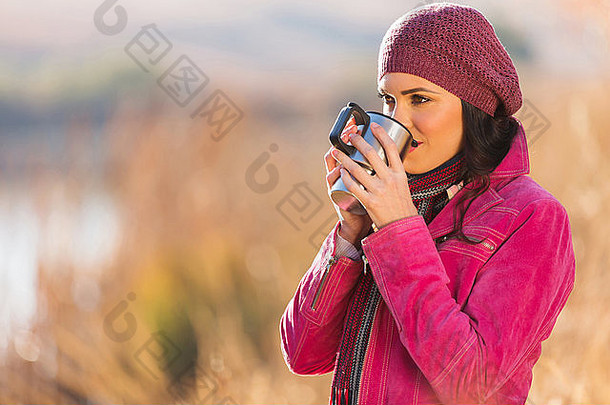 女孩喝咖啡在户外湖秋天