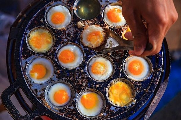 传统的泰国街快食物鹌鹑鸡蛋煮熟的加热地幔热缩进煎锅亚洲厨房美味文化烹饪零食喷火