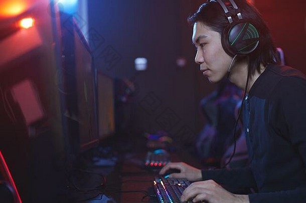 一边视图肖像年轻的亚洲男人。电脑职业游戏工作室复制空间