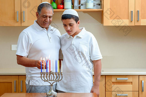 幸福家庭点燃蜡烛，共同庆祝犹太节日光明节。犹太父亲和十几岁的儿子或祖父与孙子在烛台上点燃光明节蜡烛