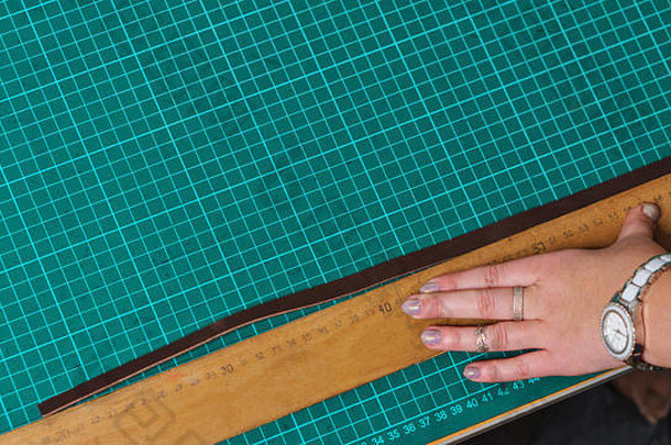 制革工测量皮革工件。车间工作流程