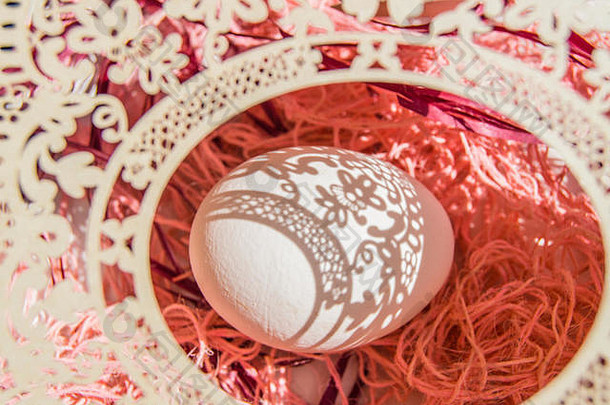 复活节贺卡以蛋和白色镂空椭圆形框架为珊瑚色背景，明亮的阳光在白色鸡蛋、文字空间和顶视图上创造出美丽的阴影