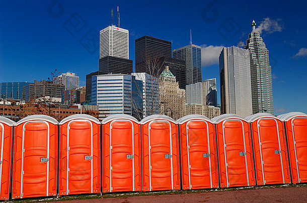 一排便携式橙色厕所紧靠多伦多市的天际线