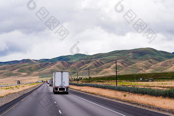 在起伏的灯芯绒小山之间，一条道路横穿平原，卡车在这条笔直的道路上行驶，这是永恒的风景