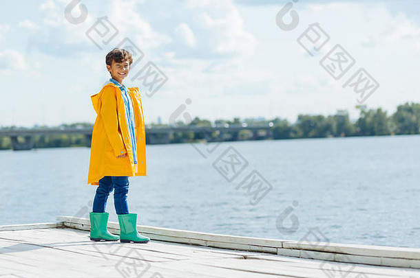 男孩穿雨衣微笑享受河视图