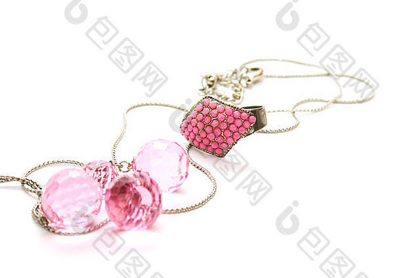 白色背景上有粉红色宝石的戒指和项链。