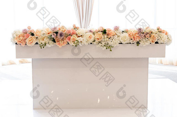 新郎和新娘的桌子靠近明亮的大窗户，用美丽的天然花朵装饰