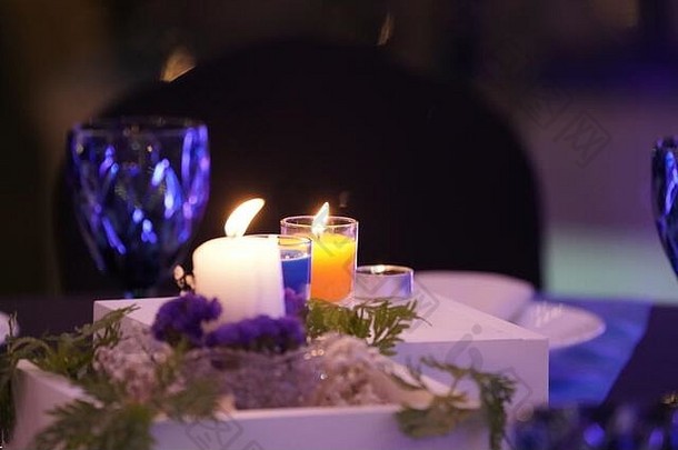 餐桌上装饰着浪漫的蜡烛，方形的白色木箱和小树在上面。