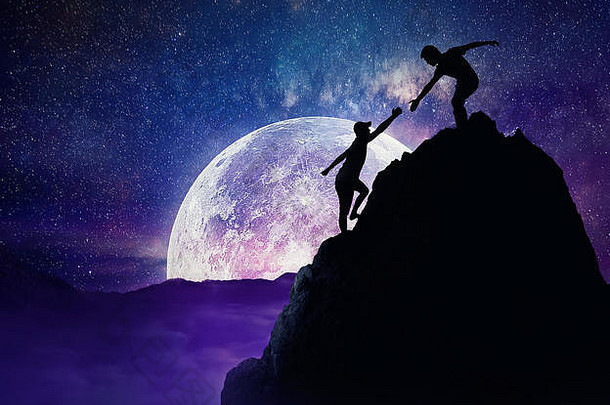 男人。给帮助手朋友爬山岩石悬崖团队合作信任概念有风险的情况完整的月亮晚上