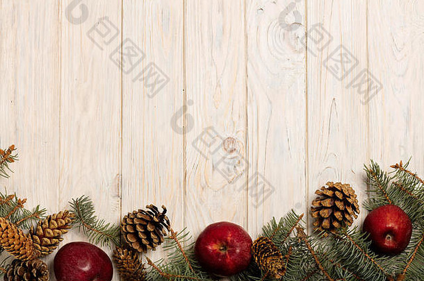 <strong>圣诞苹果</strong>和云杉枝，白色木板上有球果。