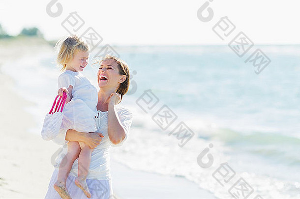 海滩上微笑的母亲和婴儿的画像