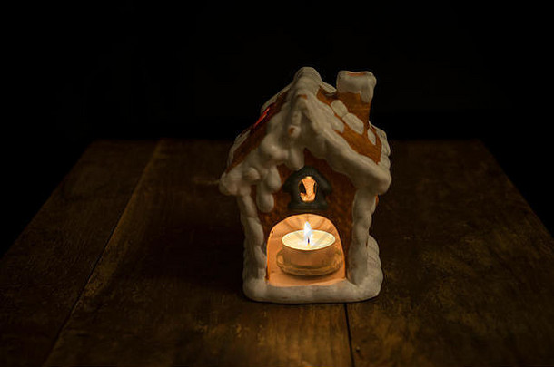 美丽的姜饼屋，烛台立在木桌上，黑色背景，圣诞装饰的美好、平静、<strong>祥和</strong>形象