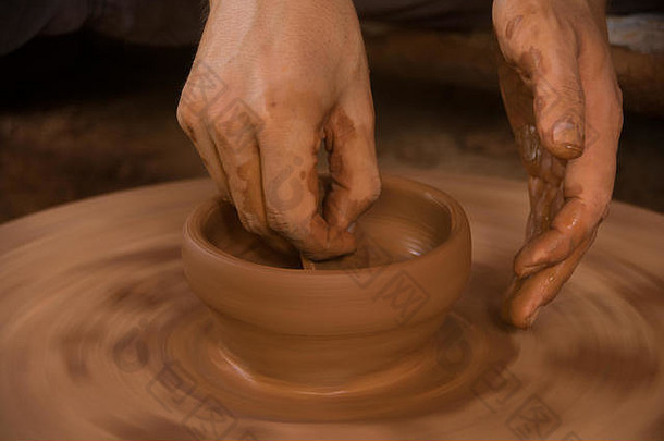 在老挝农村，两只手在一个由紫檀木制成的古代陶轮上制作陶器。