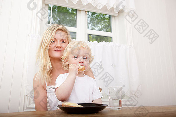 一对母子坐在桌旁一起吃午饭的肖像