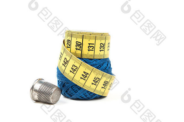 黄色的测量磁带前蓝色的缝纫线程银顶针白色背景