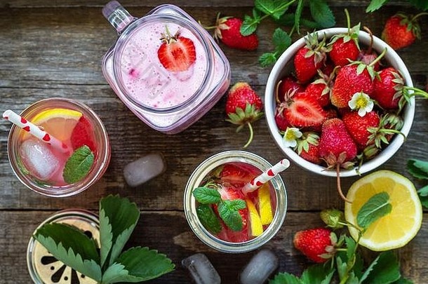 健康饮食观念。柠檬水配新鲜草莓和草莓水果酸奶冰沙或牛奶奶昔，放在乡村木桌上。俯视平面图l