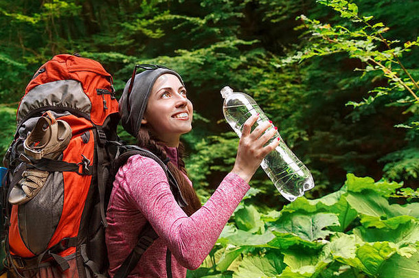 徒步旅行者女孩喝水快乐女人旅游背包喝水自然年轻的旅游女人喝水户外森林后台