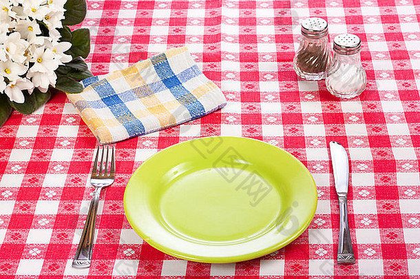 红色格子桌布上的刀、绿色盘子和叉子