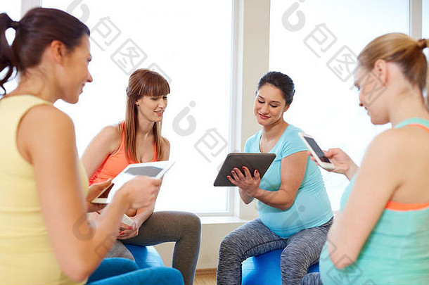在健身房使用平板电脑的快乐孕妇