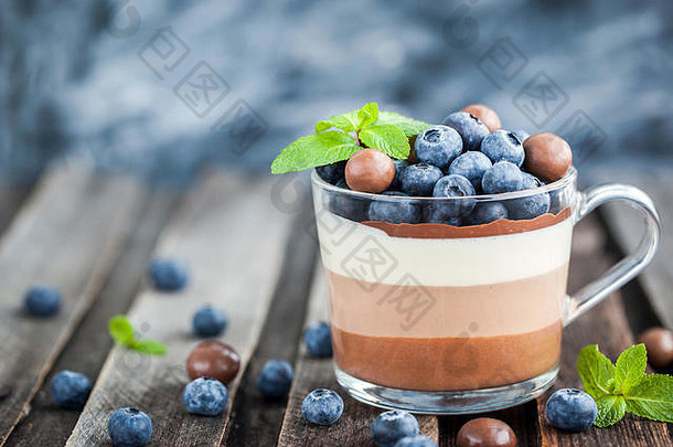 美味的三层巧克力<strong>慕斯</strong>甜点，配以新鲜蓝莓、薄荷和糖果，盛在玻璃杯中