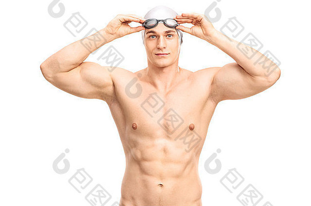 戴着灰色泳帽和黑色泳镜的肌肉发达的年轻游泳运动员看着摄像机微笑着